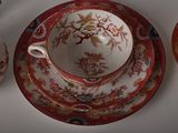 a cup and saucer sitting on a table next to a tea pot