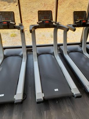 Trois appareils de cardio sont alignés dans une salle de sport