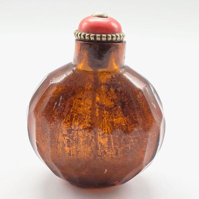 une bouteille en verre brun avec un bouchon rouge posée sur une surface blanche