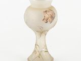 a glass vase with a flower on it on a white surface