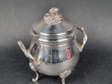 a silver teapot with a lion head on it