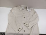 beige jacket on a white table with a tag on it