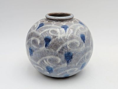 un vase bleu et blanc posé sur une surface blanche