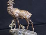 statue of a stag with antlers on a base on a black background