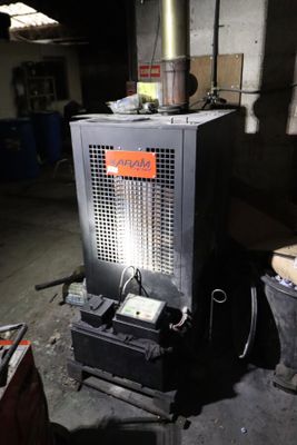 une photo d'un poêle dans un garage, sur lequel est accrochée une pancarte