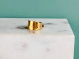 La bague en or repose sur un bloc de marbre blanc