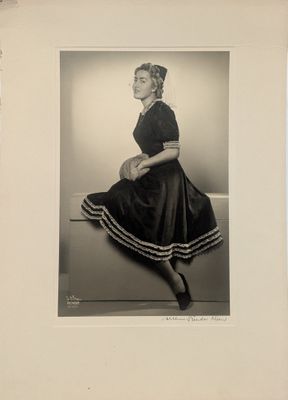 photographie en noir et blanc d'une femme en robe, assise sur un banc