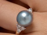 un gros plan de la main d'une personne tenant une bague ornée d'une perle
