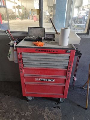 une boîte à outils rouge sur laquelle est posé un ordinateur portable, devant une fenêtre