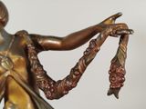 a bronze statue of a woman holding a bunch of grapes