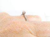 a person ' s hand holding a ring with a diamond on it