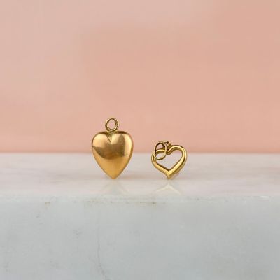 une paire de boucles d'oreilles en forme de cœur en or posées sur une surface en marbre