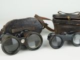 pair of antique binoculars with leather case and strap on white background