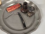 a silver plate with a razor, pepper shaker, and a razor blade on it