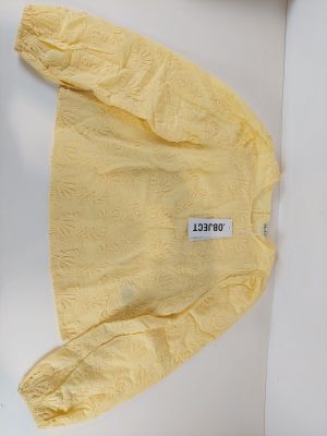 un pull jaune avec une étiquette, posé sur une surface blanche