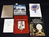 plusieurs livres posés sur une table noire, sur laquelle se trouvent une horloge et d'autres objets
