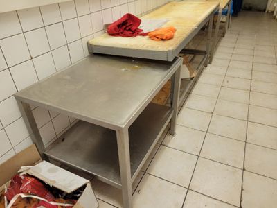 a kitchen with a table and a trash can on the floor