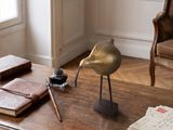 a bird statue sitting on top of a table next to a book