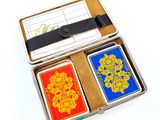 playing cards in a metal box on a white surface