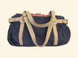 a blue purse with a tan strap and a red and white pattern