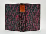 an old book sitting on top of a table covered in a pink and black cover