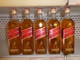 quatre bouteilles de whisky « Red Label » sur une étagère dans un magasin