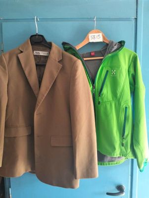 two jackets hanging on a coat rack in front of a blue door