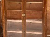 une vieille armoire en bois avec des portes vitrées dans une pièce