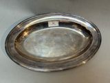 an oval silver plate on a table with a tag on it