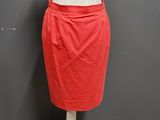a woman ' s red skirt on a mannequin stand against a gray wall