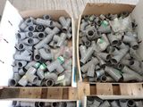 two boxes filled with gray pipe fittings on the floor