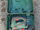 a green box with a corded cord and a tool in it