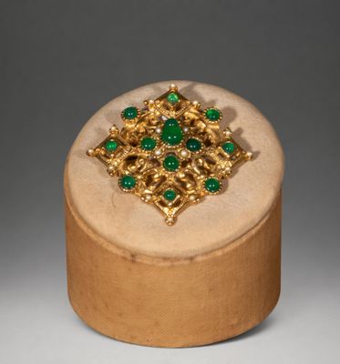 an image of a wooden box with a gold and green broochet