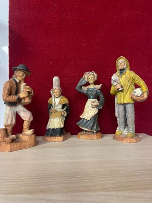 five figurines of people that are standing on a table
