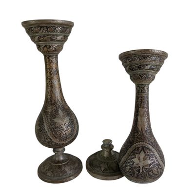 two metal vases sitting next to each other on a white surface
