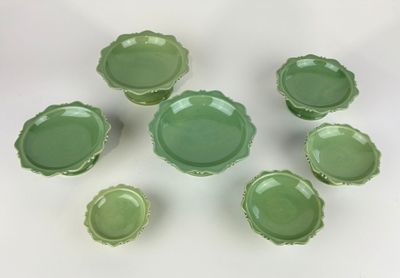 six green glass bowls and one bowl are arranged on a white surface