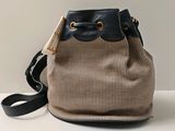 beige and black houndsered bucket bag with black leather handles