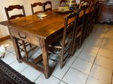une table en bois avec six chaises et un bol de fruits posé dessus