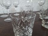 many glasses sitting on a wooden table with a white wall in the background