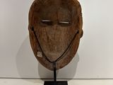 an old wooden mask on a metal stand on a white surface