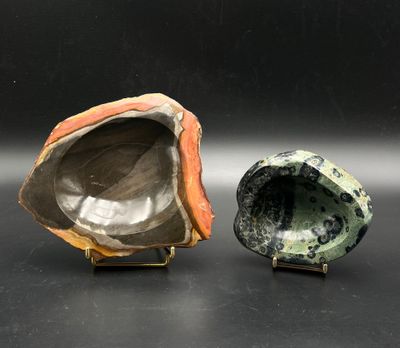 two pieces of art pottery sitting on top of a black surface