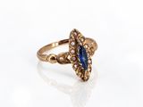a close up of a gold ring with a blue stone and pearls