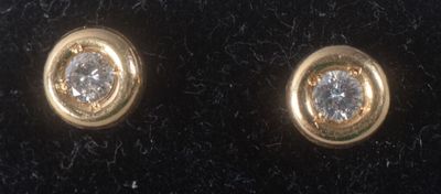 two pairs of gold and diamond stud earrings on a black velvet surface