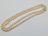 a close up of a pearl necklace on a white surface