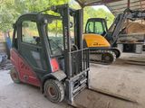 two forklifts parked in a garage with a loader in the background