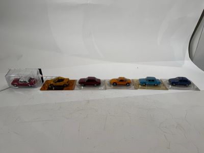 four toy cars are lined up in a row on a white surface
