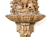 une sculpture en bois accrochée au mur, sur laquelle repose un vase