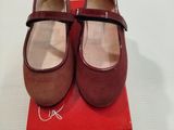 une paire de chaussures rouges posée sur une boîte rouge, elle-même posée sur une surface blanche
