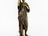 a bronze statue of a woman holding a bottle of wine