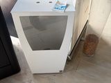 a white microwave sitting on the floor next to a black refrigerator